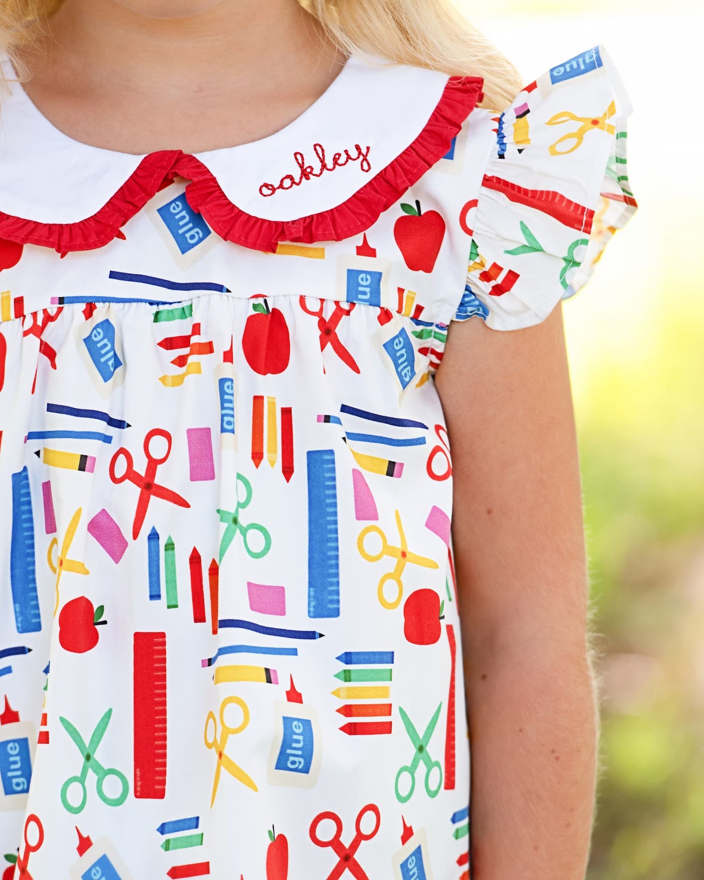 Close up of a school themed dress with an embroidered name on the collar.