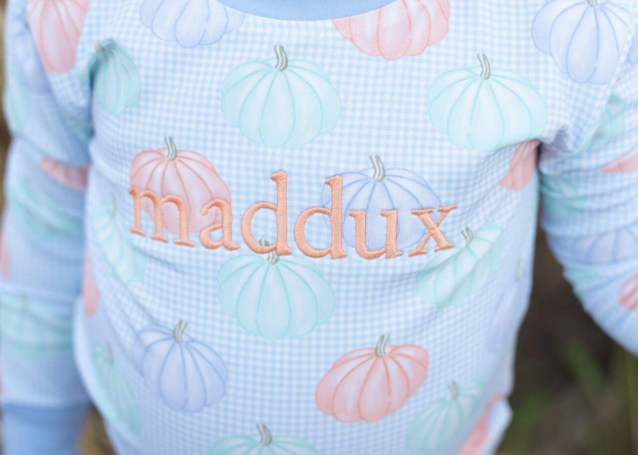 Close up pajama set with pumpkin pattern and 'maddux' text