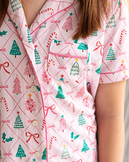 Festive women's Christmas pajamas with a playful pink holiday print featuring trees, candy canes, and bows. Soft, comfortable, and perfect for matching sibling photos and cozy holiday mornings. Shop now for the cutest Christmas PJs!