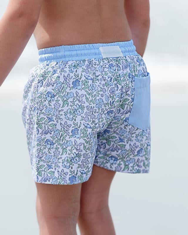 Floral-patterned swim shorts with a blue waistband on a neutral background