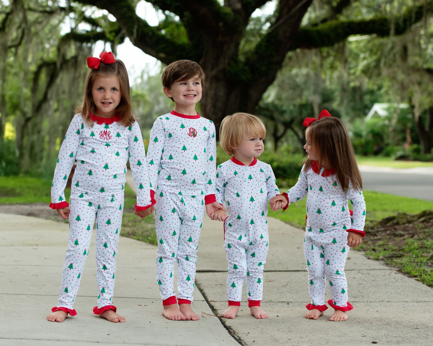 Four children in matching pajamas standing outdoors on a sidewalk.