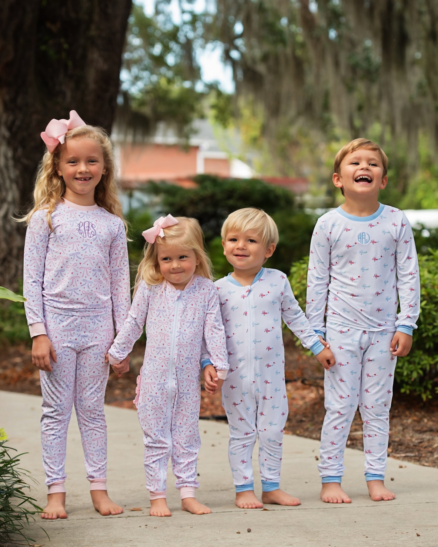 Four children wearing matching pajamas outdoors with trees in the background