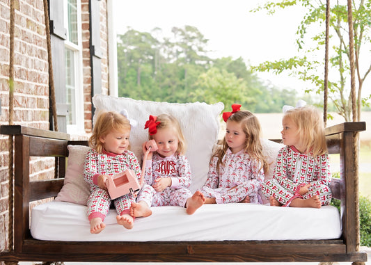 Four young girls in matching pajamas sitting on a porch swing.