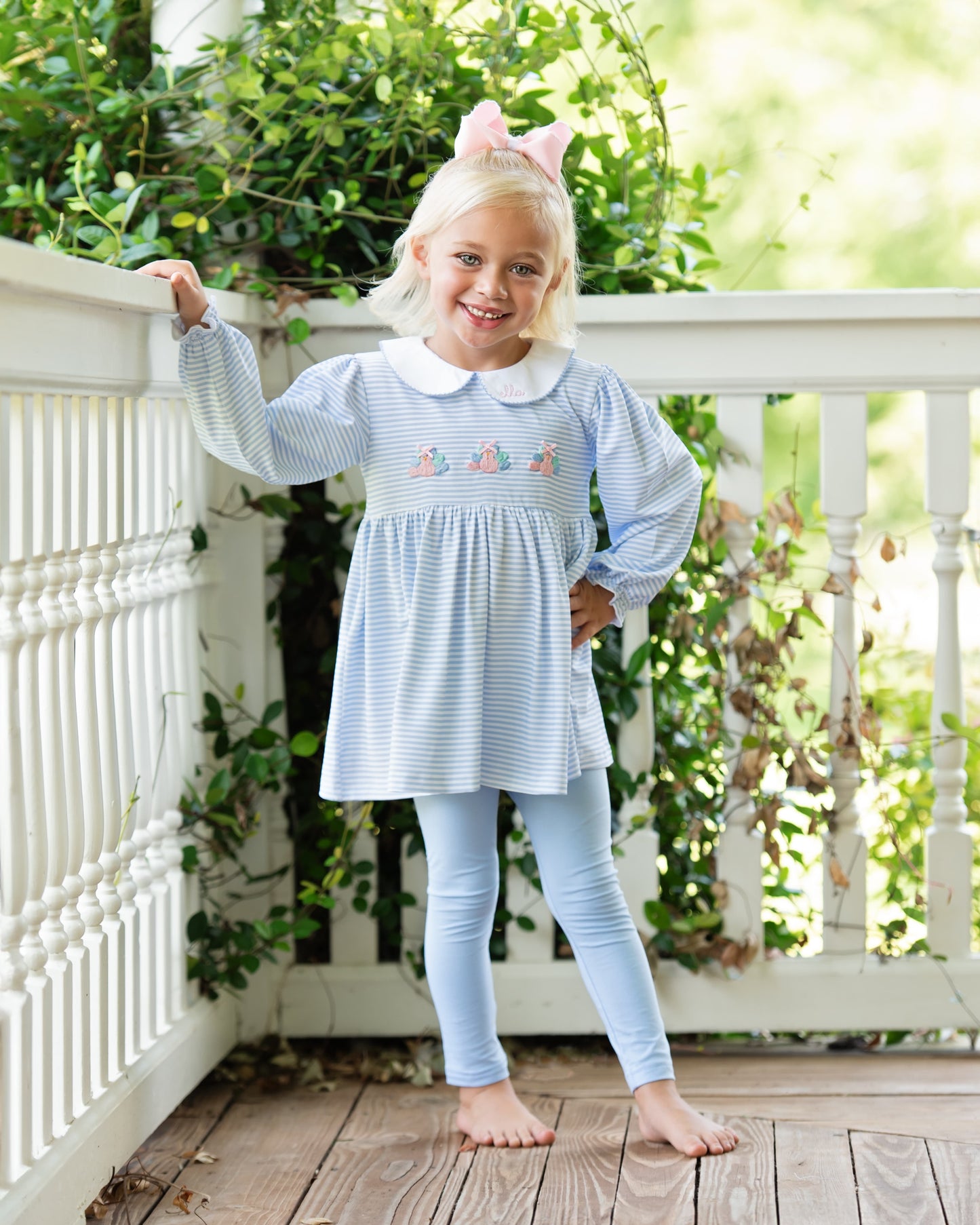 Girl in a light blue legging set with turkeys standing on a wooden deck 1.
