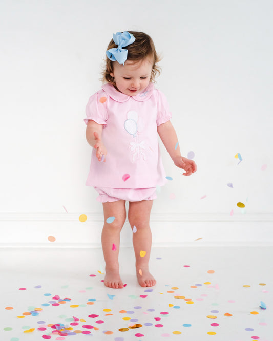 Girl in balloon outfit playing with confetti.