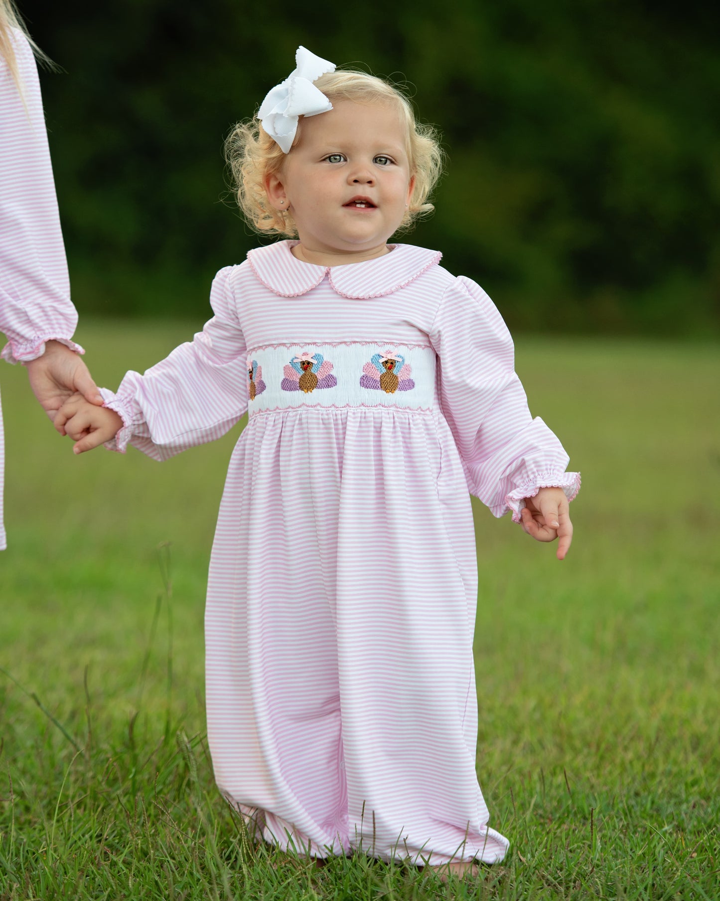 Girl wearing a pink long bubble with turkey design outdoors
