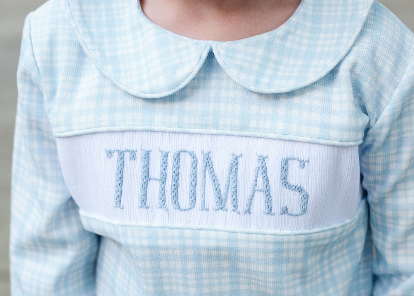 Light blue checkered shirt with embroidered name 'THOMAS' on a plain background