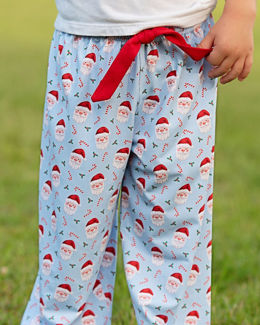 Light blue pajama pants with Santa Claus pattern and red drawstring on a grassy background