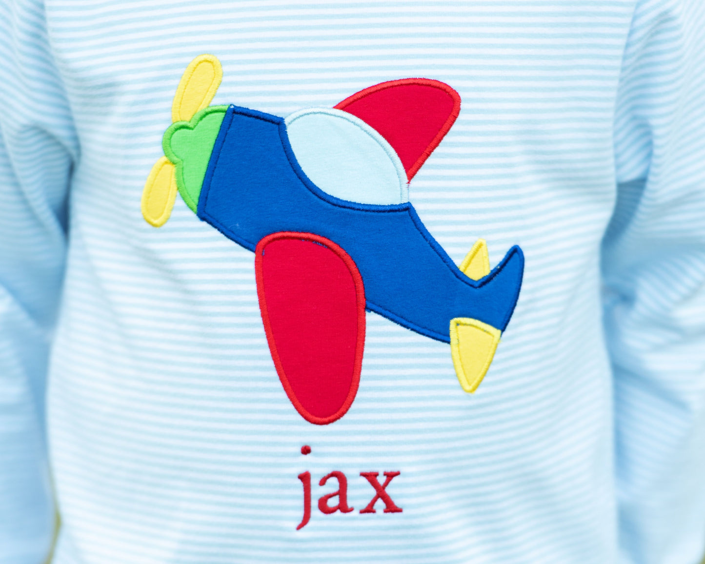 Light blue shirt with a colorful airplane patch and 'jax' text