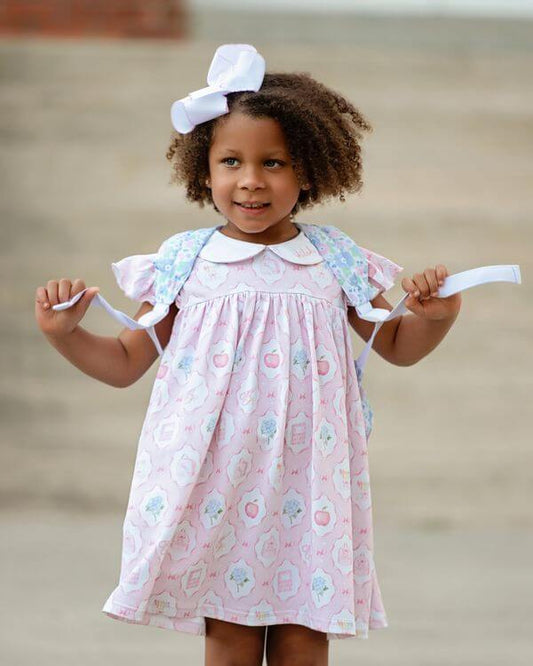 girl wearing dress with school motifs and a backpack