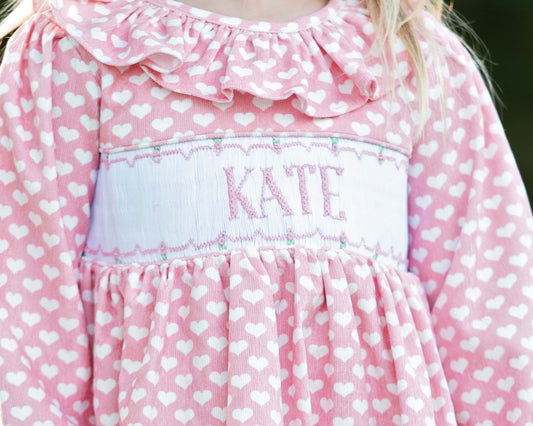 Pink heart dress with white heart pattern and 'KATE' smocking