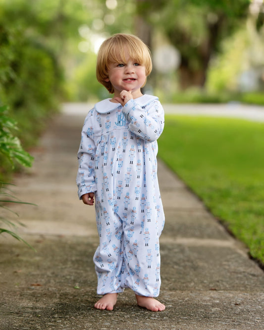 Small child standing on a sidewalk wearing a nutcracker theme romper