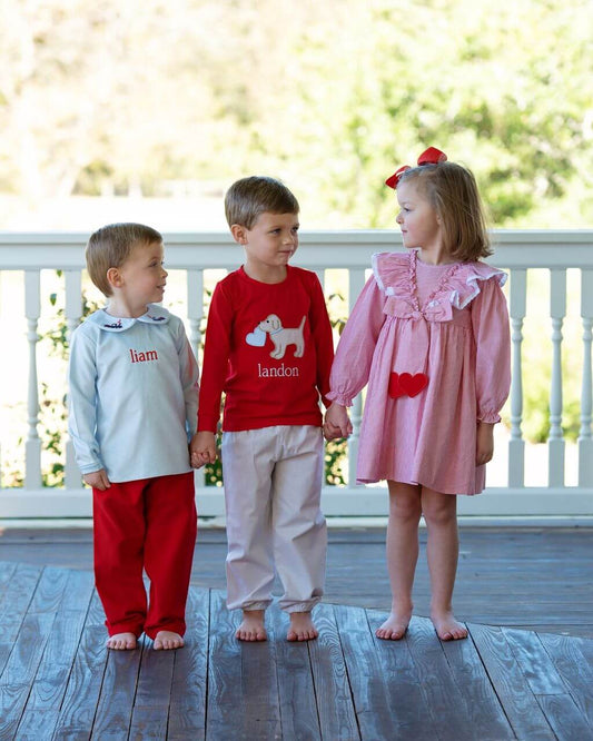 Three children holding hands on a wooden deck