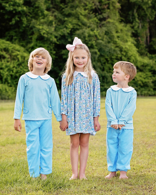 Three kids wearing matching outfits in a grassy field