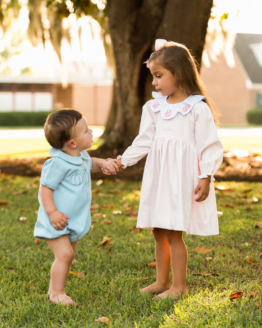Two_children_holding_hands_in_a_grassy_area_with_trees_in_the_background