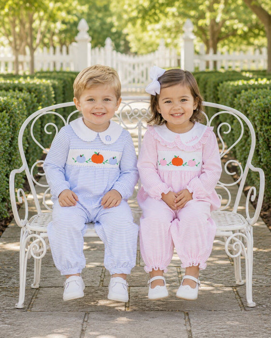 Two children in matching outfits sitting on a white bench outdoors.