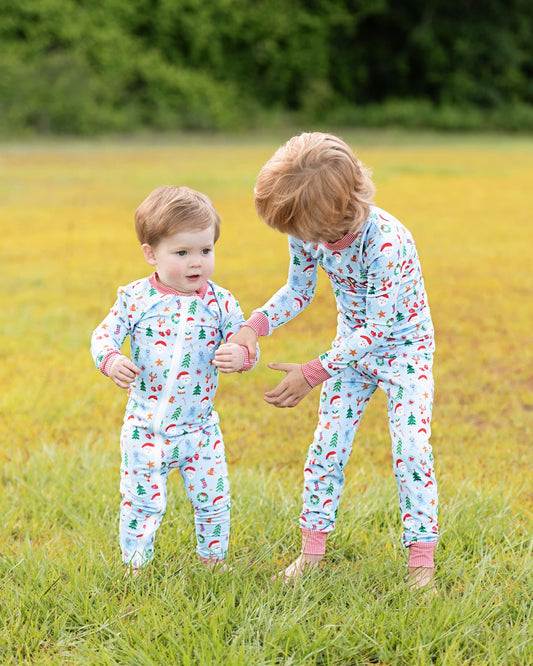 Two children in matching pajamas standing in a grassy field.
