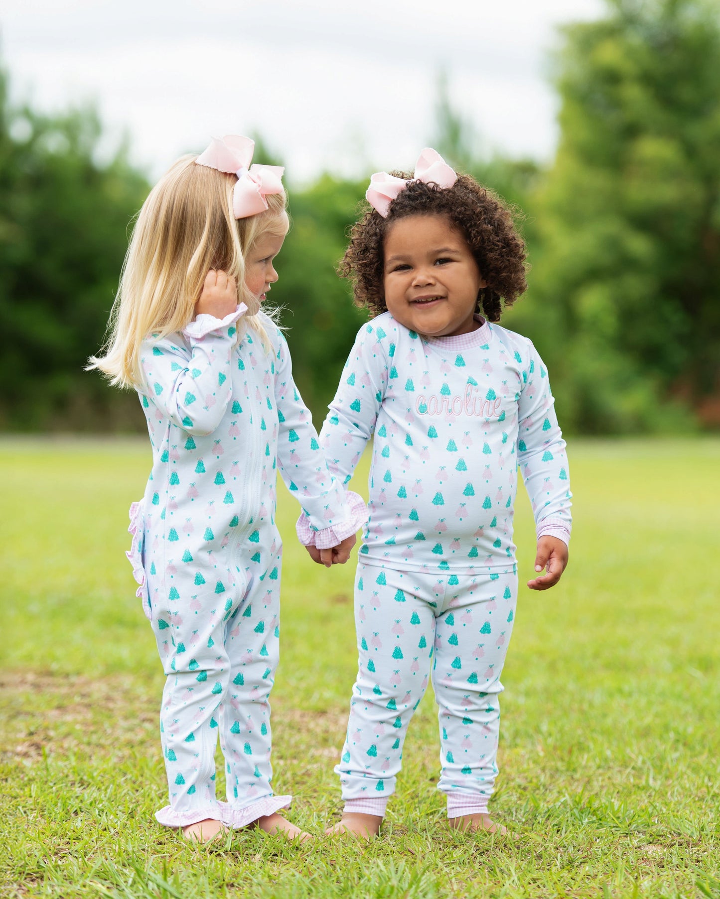 Two children in matching pajamas standing in a grassy field.