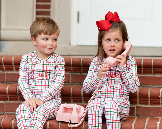 Two children in matching pajamas with 'nude' and 'ampella' text, sitting on a staircase.