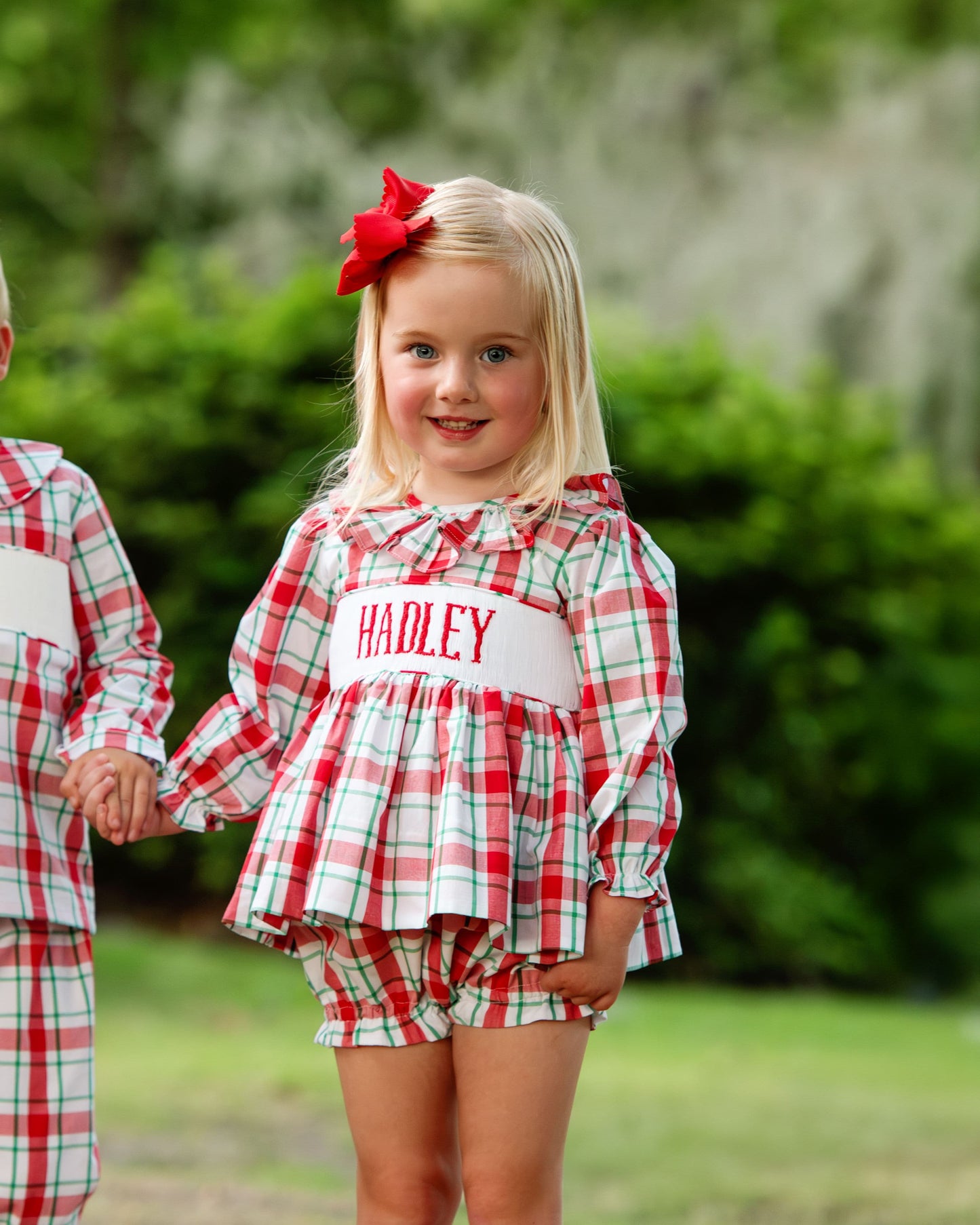 Two children in matching red and green plaid outfits outdoors.