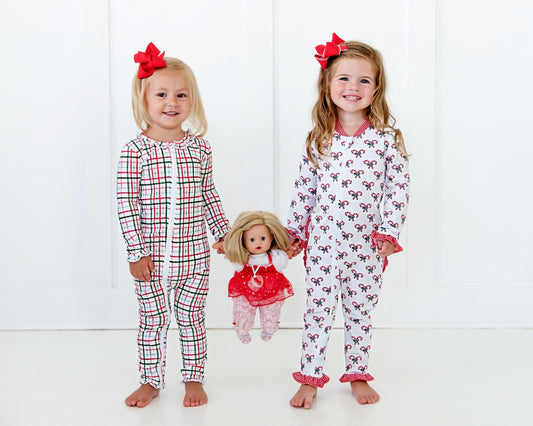 Two children in pajamas holding a doll on a white background