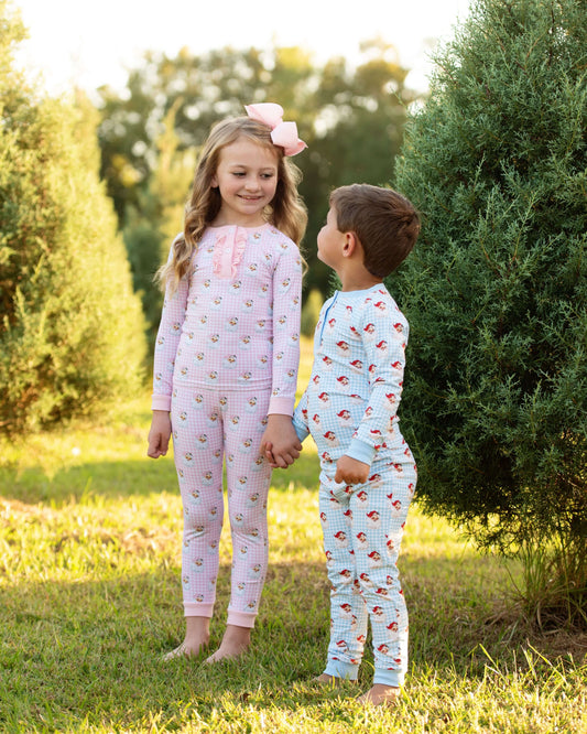 Two children in pajamas standing outdoors with trees in the background