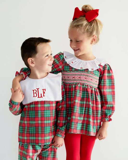 Two children in red and green plaid outfits with a white bib and red bow.