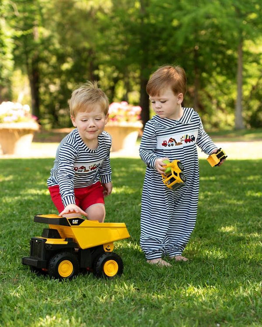 Two children playing with toy trucks on a grassy area