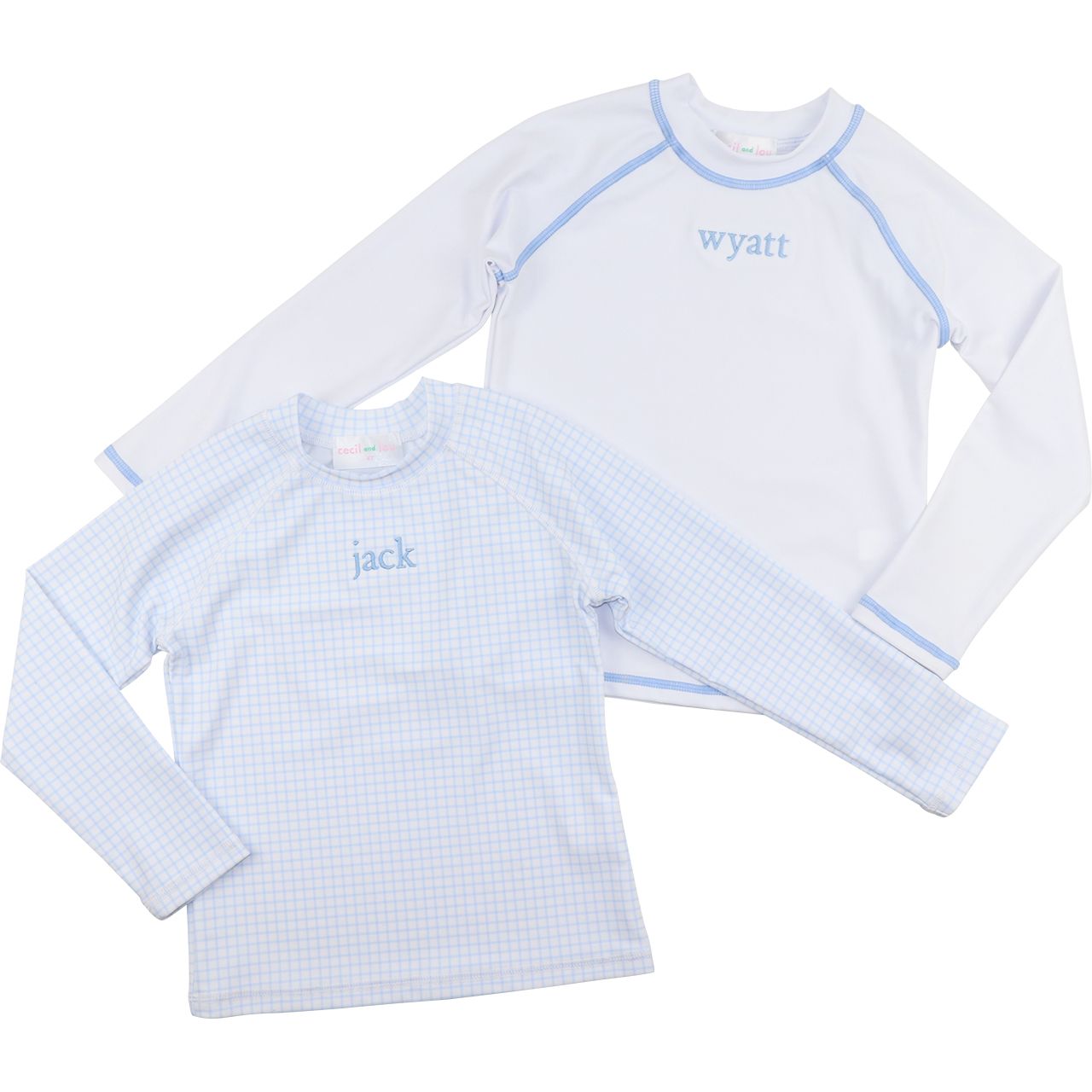 Two children's long-sleeve shirts with embroidered names on a white background