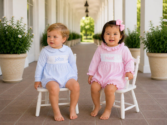 Two children sitting on small chairs outdoors with potted plants around.