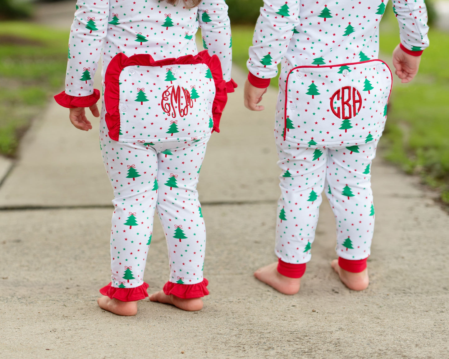 Two children wearing Christmas-themed pajamas with red monogram.