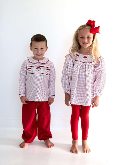 Two children wearing matching pajama sets with Santa hats on a white background