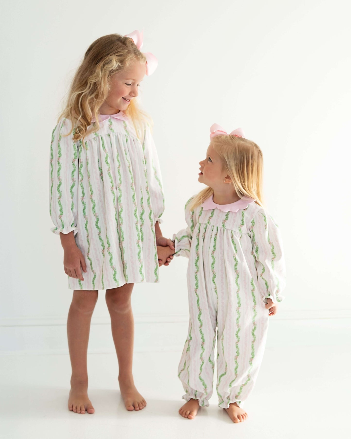 Two children wearing matching pajamas with green wavy patterns on a white background