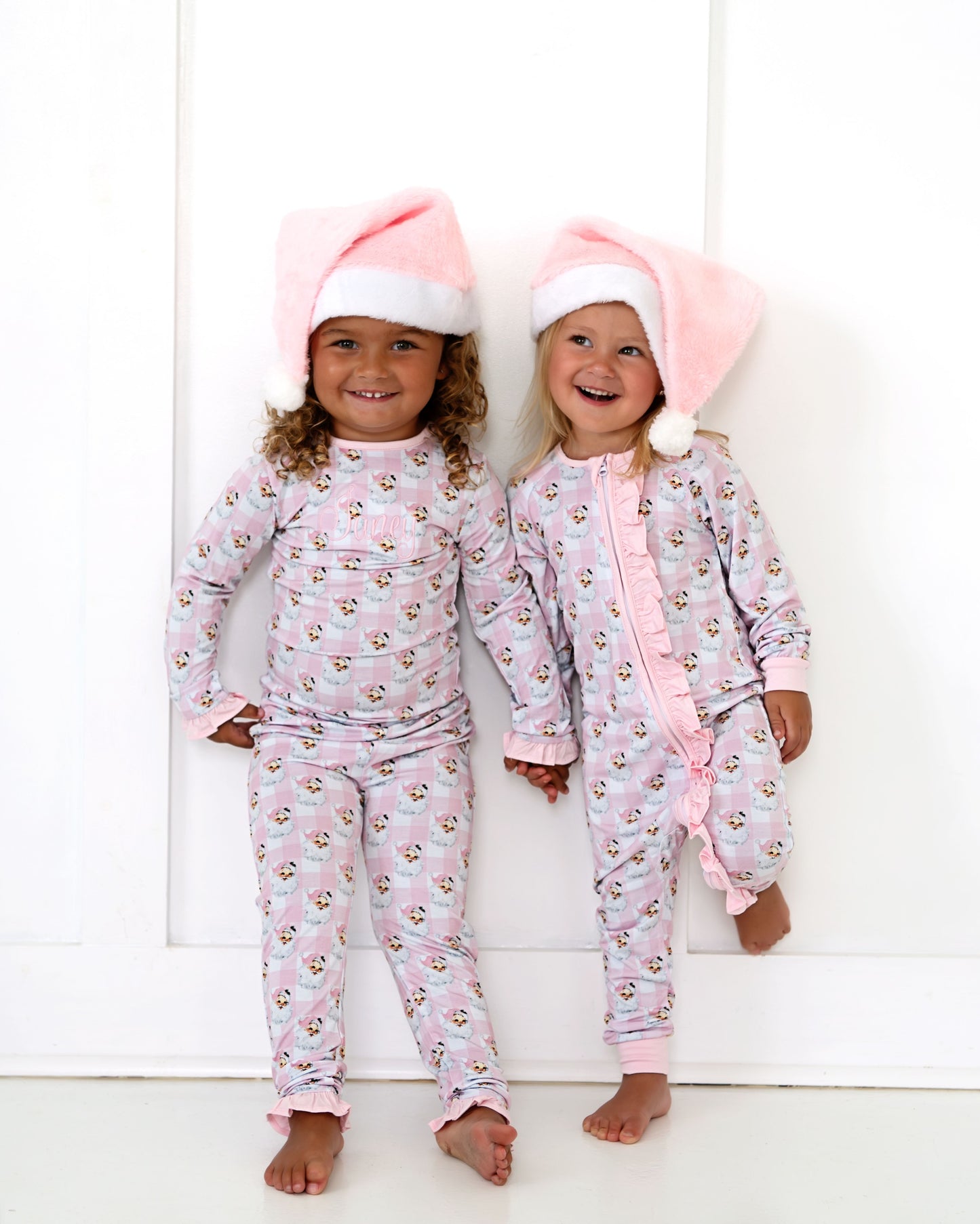 Two children wearing matching pink pajamas with animal prints against a white background.