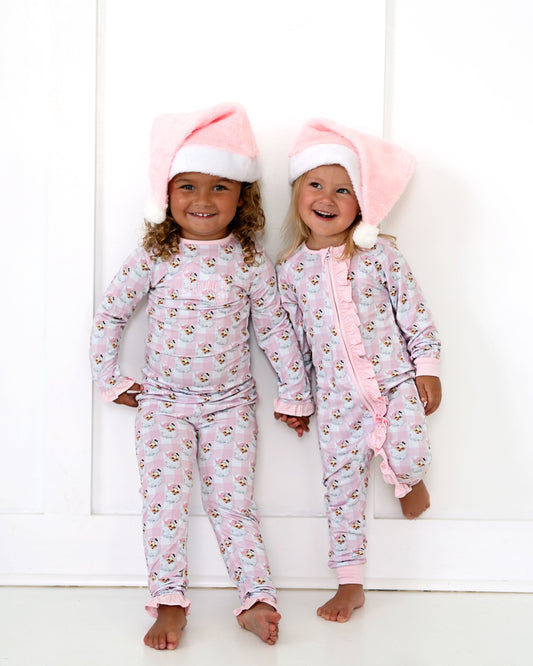 Two children wearing matching pink pajamas with animal prints against a white background.