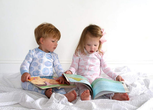 Two children wearing matching pumpkin zipper pajama