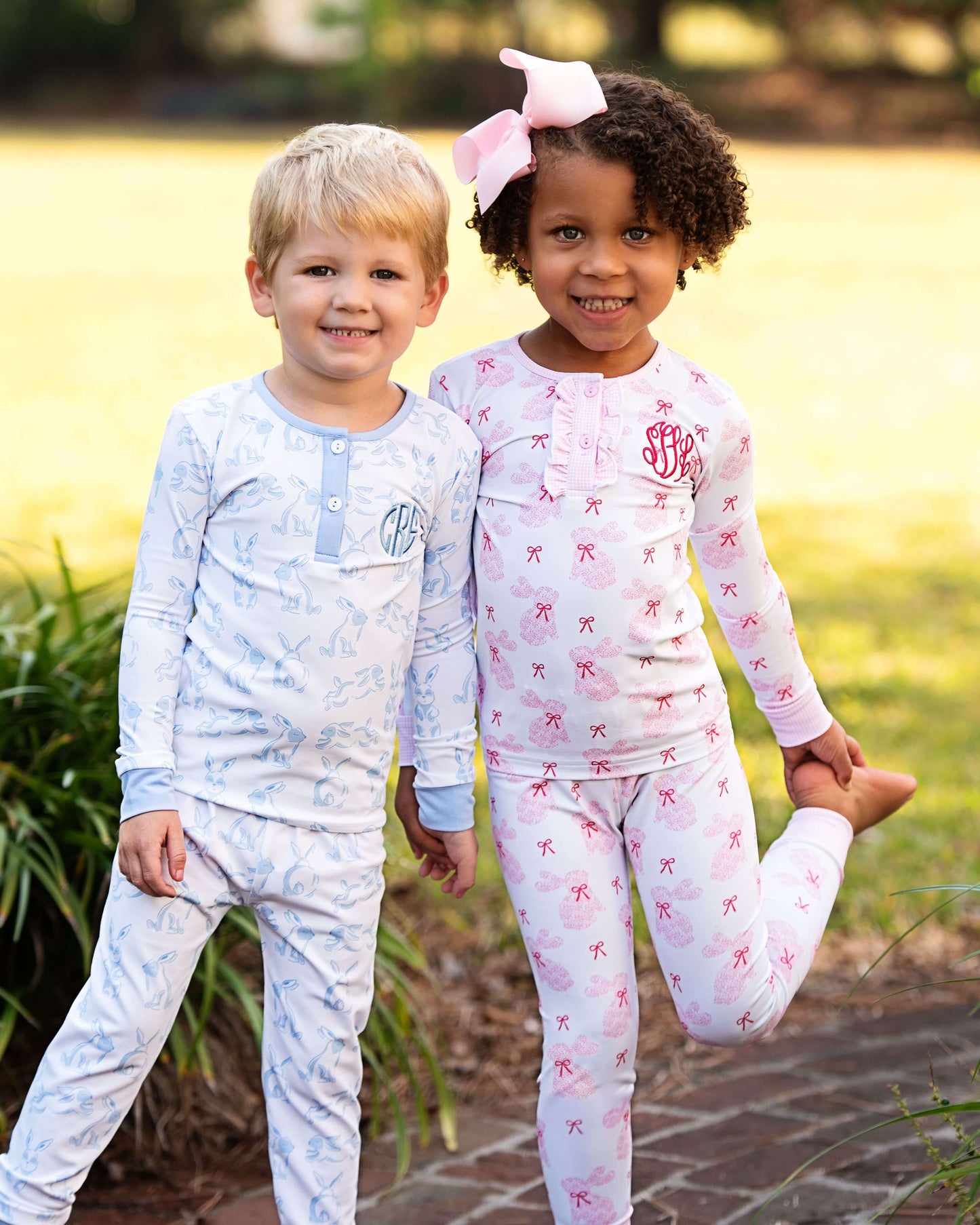 Two children wearing pajamas outdoors with a blurred natural background