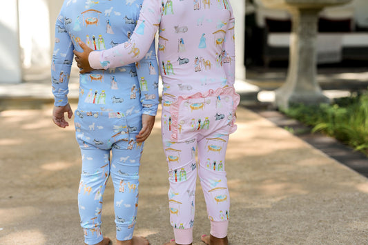 Two children wearing patterned pajamas standing outdoors on a path.