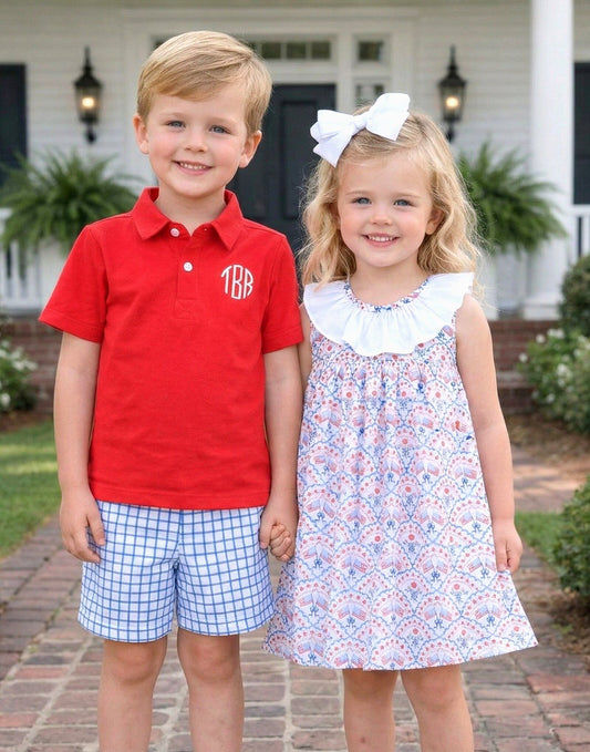 Two kids holding hands smiling standing in front of a white house.