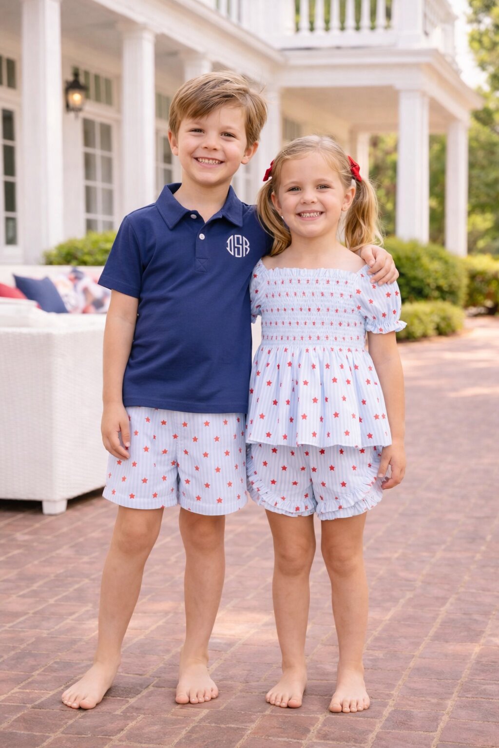 Two kids in matching star print outfits standing next to one another smiling.