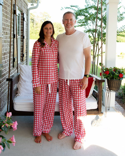 Two people wearing red and white checkered pajamas standing on a porch.