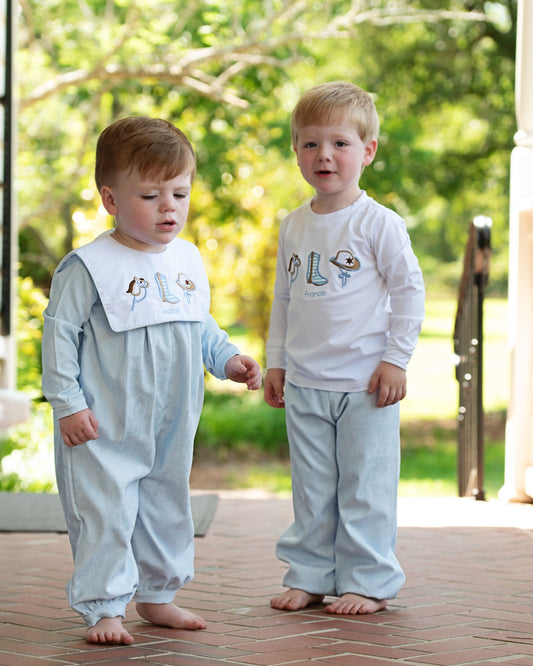 Two young boys wearing matching pajama sets outdoors on a sunny day.