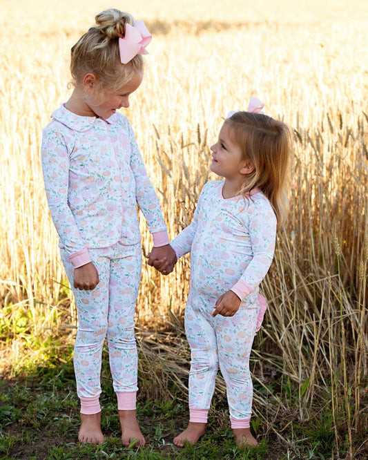 Two young girls in matching pajamas standing in a field of tall grass 1