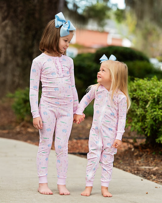 Two young girls wearing matching birthday pajamas with a garden background