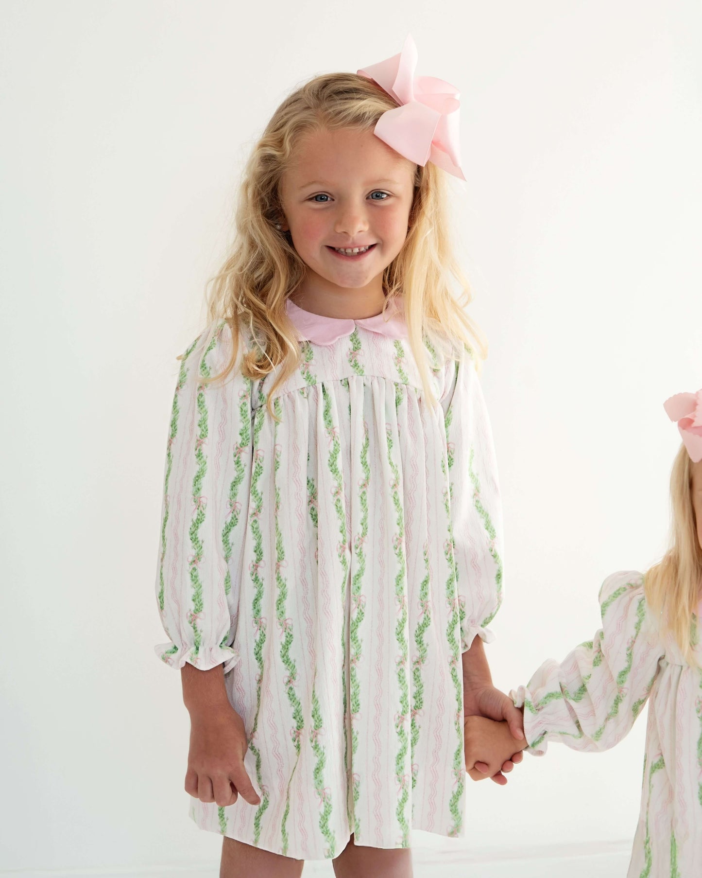 Two young girls wearing matching pajamas with a white background
