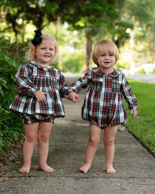 Two young kids standing barefoot on a sidewalk wearing matching outfits