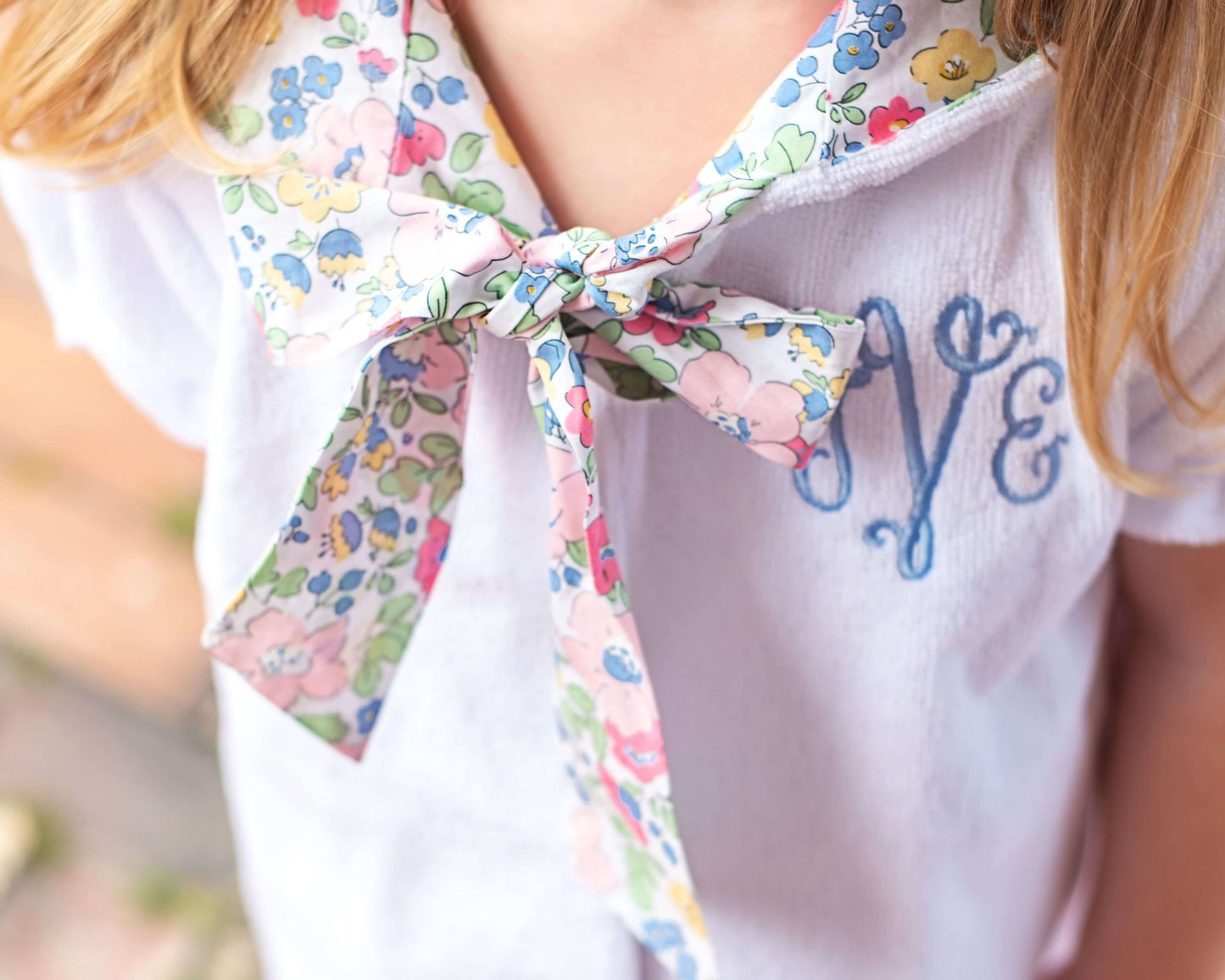 White blouse with floral scarf and embroidered name on a blurred background