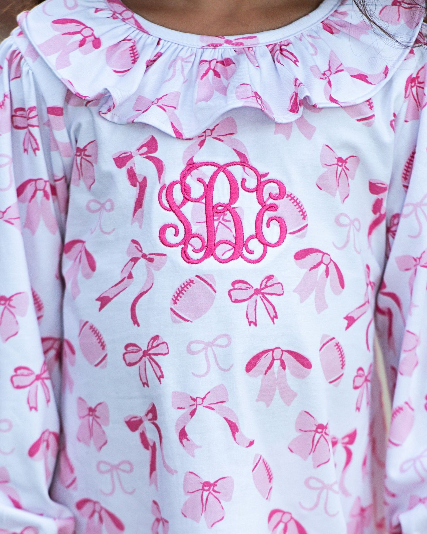 White shirt with pink bow pattern and monogram on a hanger