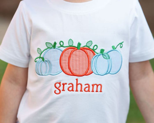 White t-shirt with colorful pumpkins and the name 'graham' on a blurred background