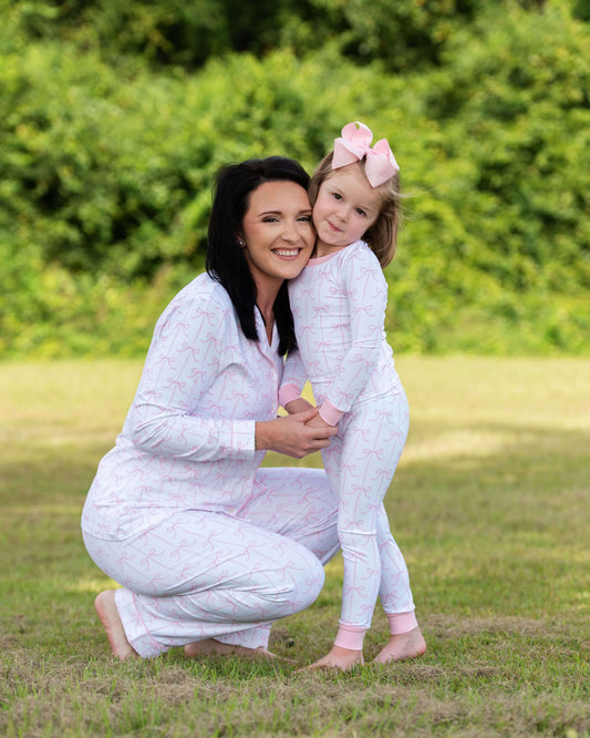 Woman and child in matching outfits outdoors with greenery in the background